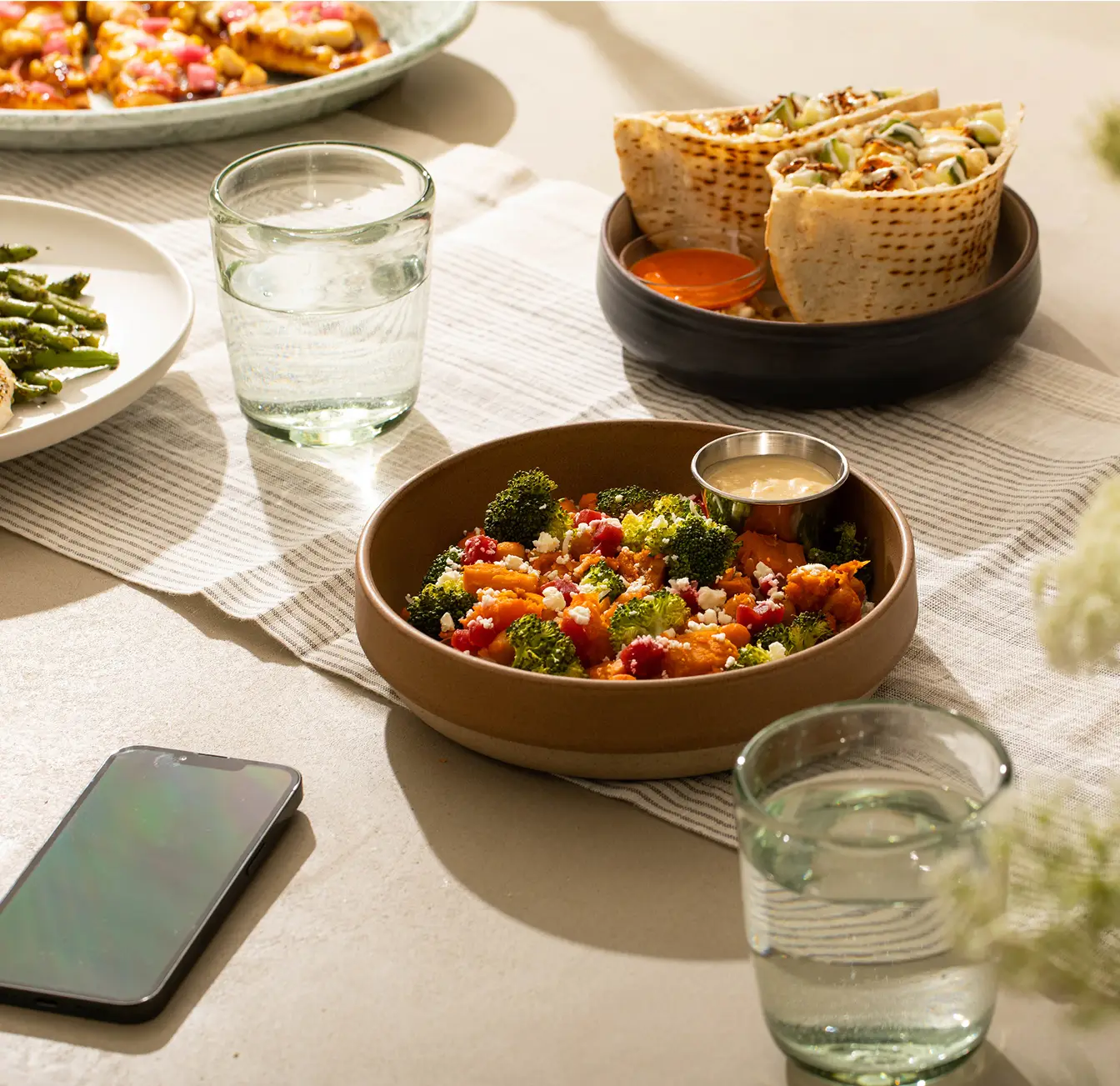 Bowl of food on a table with a smartphone in the background